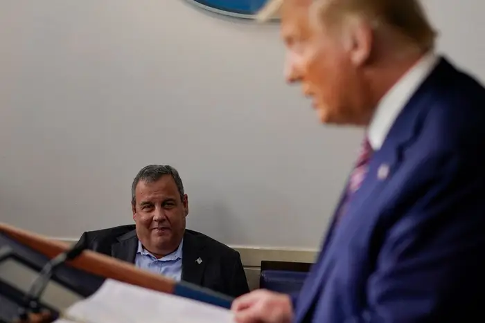 Chris Christie watches Donald Trump in the press briefing room
